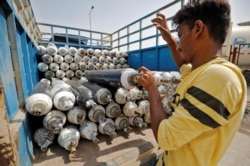 A worker loads empty oxygen cylinders onto a supply van to be transported to a filling station, at a COVID-19 hospital, amidst the spread of the coronavirus disease (COVID-19) in Ahmedabad, India, April 22, 2021.