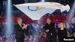 International Olympics Committee President Thomas Bach, left, applauds as Pyeongchang Mayor Lee Sok-ra, second right, waves Olympic flag during the closing ceremony for Sochi 2014 Winter Olympics, Feb. 23, 2014.