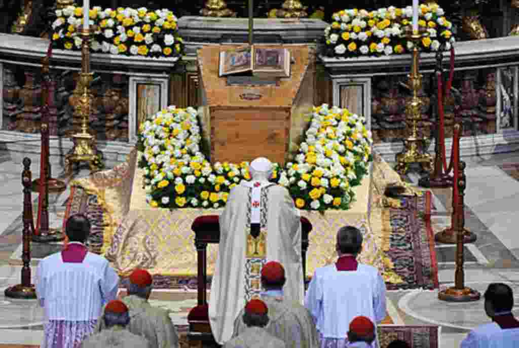 El papa Benedicto XVI se arrodilla frente al ataúd que contiene los restos de Juan Pablo II.