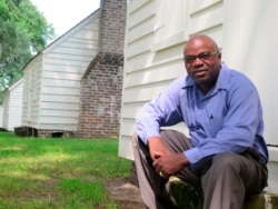 FILE - Joe McGill, who works with the National Trust For Historic Preservation, sits outside one of the slave cabins at McLeod Plantation in Charleston, S.C., Aug. 14, 2013.