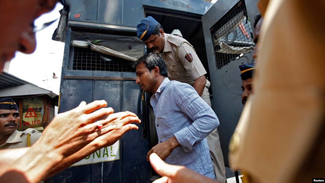 Policemen escort one of the four men convicted of raping a photojournalist outside a jail in Mumbai, March 20, 2014. 