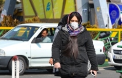 A woman wearing a protective mask crosses a street in Iran's capital Tehran, Feb. 22, 2020.