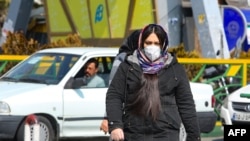 A woman wearing a protective mask crosses a street in Iran's capital Tehran, Feb. 22, 2020.