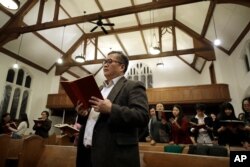 Baptist Pastor Clifford Maung, front, an immigrant from Myanmar, also known as Burma, sings a hymn with members of his congregation at the Overseas Burmese Christian Fellowship in Boston, Feb. 16, 2020.