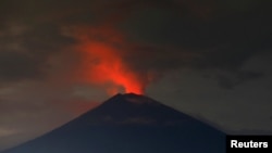 Lava, inside the crater of Mount Agung, reflects off the volcano's ash and clouds, while it erupts, as seen from Amed, Karangasem Regency, Bali, Indonesia, Nov. 30, 2017. 