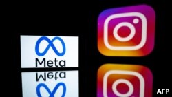FILE - This photograph taken on Jan. 12, 2023, shows a smartphone and a computer screen displaying the reflected logos of Instagram app and its parent company Meta in Toulouse, south-western France.