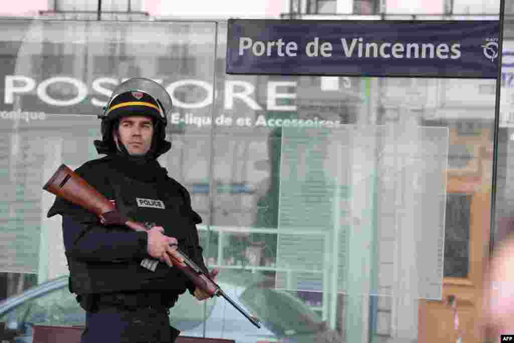An armed member of the French riot police (CRS) takes up position at Porte de Vincennes in Paris, Jan. 9, 2015, after at least one person was injured when a gunman opened fire at a kosher grocery store and took at least five people hostage.