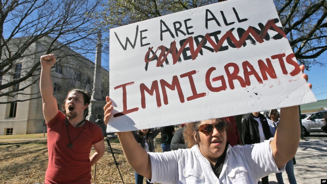 Protesters chant outside the Grayson County courthouse in Sherman, Texas, Feb. 16, 2017. In an action called "A Day Without Immigrants," immigrants across the country are expected to stay home from school, work and close businesses to show how critical they are to the U.S. economy and way of life. 