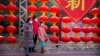 Personas con máscaras médicas posan para la foto frente a decoraciones de una feria de un templo cancelada con motivo del Año Nuevo Lunar en el Parque Longtan, en Beijing, el sábado 25 de enero de 2020. (AP Foto/Mark Schiefelbein)