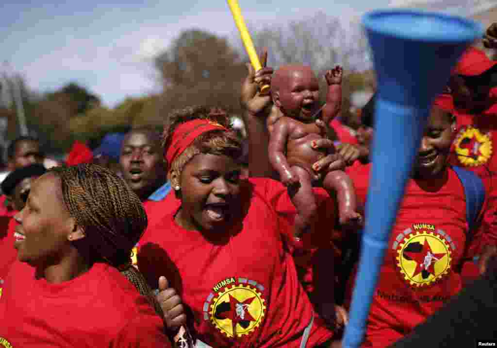 A member of the National Union of Metalworkers of South Africa (NUMSA) holds a baby doll as strikers march in Cape Town, Sept. 9, 2013.&nbsp;