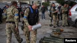 Policajac nosi kutiju sa antipešadijskom minom u gradu Zoločiv