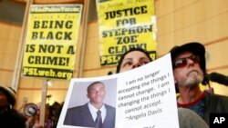 Anita ross sostiene una foto de Stephon Alonzo Clark, durante una protesta a la entrada de Sacramento, el jueves 22 de marzo de 2018. Clark murió tiroteado por policías de la ciudad que respondieron a una denuncia contra un hombre que estaba destruyendo vehículos.