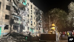 FILE - In this photo released by Ukraine's National Police, onlookers gather after a Russian strike on a residential building in Kharkiv, Ukraine, Oct. 2, 2024. A U.N. report issued on Jan. 8, 2025, accuses Russia of carrying out a policy of mass destruction against Ukraine.