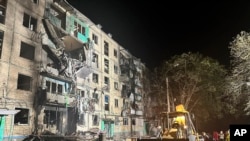 La gente se reúne alrededor de los daños y escombros después de un ataque ruso a un edificio residencial en Járkov, Ucrania, la noche del 2 de octubre de 2024.