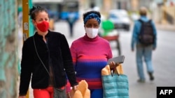 Dua perempuan terlihat memakai masker wajah saat berjalan setelah membeli roti di Havana, pada 2 Februari 2021, ketika kasus COVID-19 melonjak di negara kepulauan itu. (Foto: AFP)