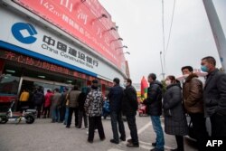 Customers lining up to have their temperature taken before entering the bank in Nantong, China, Feb. 25, 2020. The bank was controlling the number of people inside the bank at any one time as a precaution against the COVID-10 coronavirus.