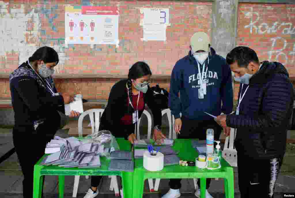 Previo a la apertura de un colegio electoral miembros de las mesas recolectoras de votos se preparan para recibir a los votantes en La Paz, Bolivia.