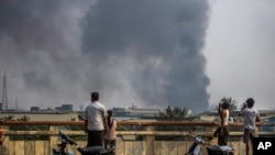 File - Black smoke billows from the industrial zone of Hlaing Thar Yar township in Yangon, Myanmar March 14, 2021, as attacks on Chinese-run factories in Myanmar's biggest city drew demands from Beijing for protection for their property and employees.