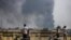 File - Black smoke billows from the industrial zone of Hlaing Thar Yar township in Yangon, Myanmar March 14, 2021, as attacks on Chinese-run factories in Myanmar's biggest city drew demands from Beijing for protection for their property and employees.