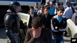 FILE - Police block a road out of Simferopol, Crimea, May 18, 2015, while young Tatars walk away during a march to mark the 71st anniversary of Soviet dictator Stalin's 1944 mass deportation of Crimean Tatars. 