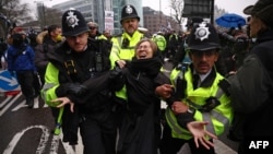 Sejumlah polisi mengamankan seorang pedemo yang mencoba menghalangi jalan di lokasi bekas lokasi Royal Mint di London dalam unjuk rasa memprotes pembangunan gedung kedubes baru, Sabtu, 8 Februari 2025. 