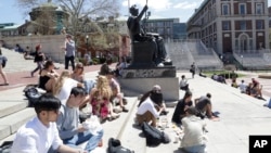 FILE - Students gather on the steps of Columbia University's Low Memorial Library next to Daniel Chester French's sculpture, Alma Mater, April 29, 2015 in New York. (AP Photo/Mark Lennihan)