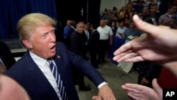 FILE - FILE - In this Aug. 11, 2015, file photo, Republican presidential candidate Donald Trump meets supporters after addressing a GOP fundraising event in Birch Run, Mich.