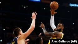 La vedette des Lakers et de la NBA, LeBron James, à droite, contre Nikola Jokic des Denver Nuggets, Los Angeles, Californie, le 25 octobre 2018. 