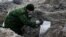 A soldier from a special "search battalion" of Belarus Defense Ministry takes part in the exhumation of a mass grave containing the remains of about 730 prisoners of a former Jewish ghetto, discovered at a construction site in the center of Brest, Feb. 26, 2019.