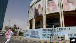 一名男子走过沙特阿拉伯利雅得一栋有沙特领导人头像的大楼（2016年4月19日）