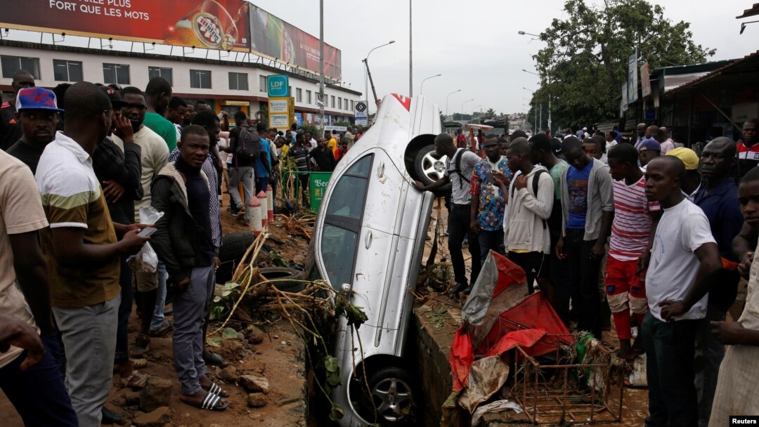 Abantu bashengereye imodoka yatwawe n'imvura i Abidjan, Cote d'Ivuware. 