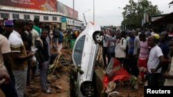 Abantu bashengereye imodoka yatwawe n'imvura i Abidjan, Cote d'Ivuware. 