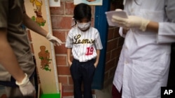 Un niño, con una mascarilla para protegerse del COVID-19, asiste a campaña de vacunación organizada por el Ministerio de Salud, en el barrio El Valle de Caracas, Venezuela, el viernes 20 de noviembre de 2020.