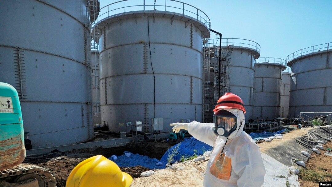 Menteri Ekonomy, Perdagangan dan Industri Jepang, Toshimitsu Motegi (kanan), mengenakan pakaian pelindung dan masker, meninjau tanki air yang terkontaminasi di PLTN Daiichi Fukushima (26/8). Tingkat radiasi di PLTN tersebut dilaporkan telah melonjak ke tingkat potensi bahaya hanya dalam waktu satu minggu, Sabtu (31/8).