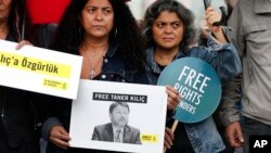 FILE - Human rights activists stage a protest outside a court where 11 human rights activists, among them Amnesty International's Turkey chairman Taner Kilic, are on trial, accused of belonging to and aiding terror groups, in Istanbul, Turkey, Oct. 25, 2017.