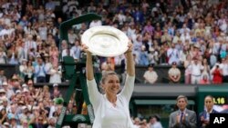 Romania's Simona Halep holds the trophy after defeating United States' Serena Williams during the women's singles final match on day twelve of the Wimbledon Tennis Championships in London, Saturday, July 13, 2019. 