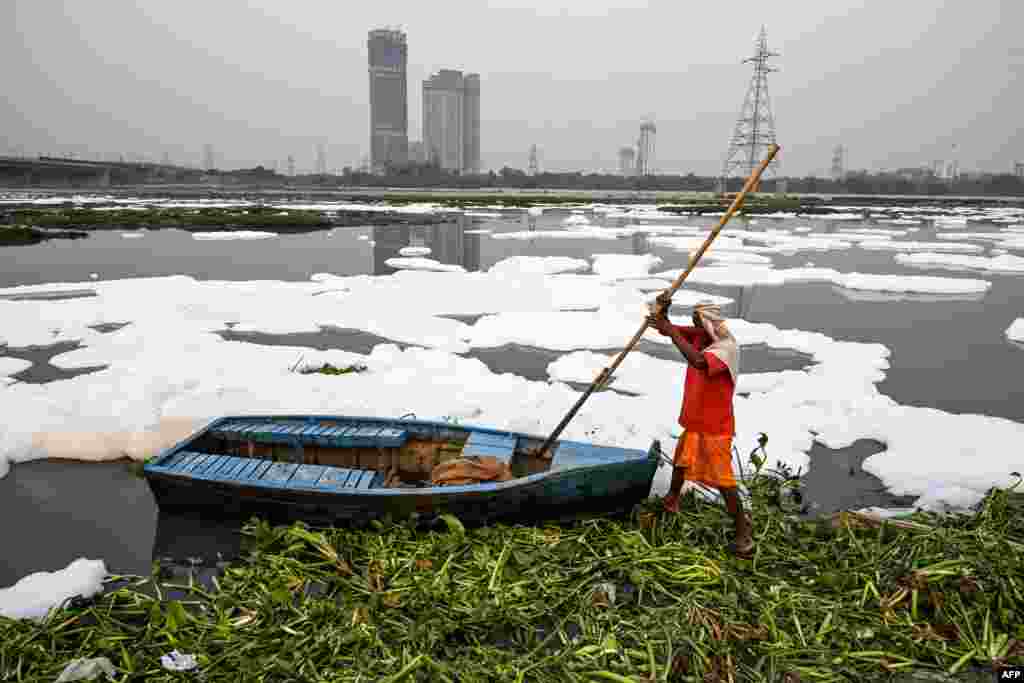 오염으로 거품에 덮인 인도 야무나 강에서 한 남성이 보트를 정박하고 있다.