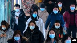 FILE - Commuters wearing face masks to protect against the spread of the coronavirus walk through a subway station in Beijing, March 3, 2021. 