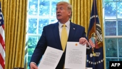 US President Donald Trump shows a letter from Chinese President Xi Jinping as he announces and initial deal with China while meeting the special Envoy and Vice Premier of the People's Republic of China Liu He