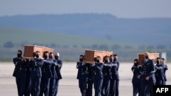 Spanish air force personnel carry the coffins with the bodies of Spanish journalists David Beriain and Roberto Fraile and Irish ONG chief Rory Young, killed in eastern Burkina Faso, after arriving in the Torrejon de Ardoz air base on April 30, 2021. 