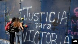 Mujeres jóvenes colocan flores en el muro perimetral de las oficinas del estado de Quintana Roo rociadas con grafitis que piden "Justicia para Victoria", durante una protesta en la Ciudad de México, México. Marzo 29, 2021. Foto: AP.