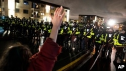 Un manifestante levanta las manos frente a un cerco policial mientras desafían una orden de dispersarse durante una protesta el lunes, 12 de abril, por la noche.