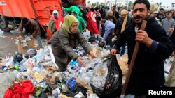 Des manifestants aident les travailleurs de la municipalité à débarrasser des tas d'ordures devant le bureau du Premier ministre à la Kasbah, la vieille ville de Tunis, le 27 janvier 2011