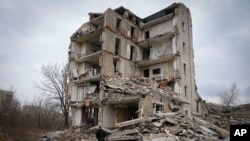 FILE— Local resident Yevhen, 34, looks at his home in an apartment house damaged in 2022 heavy battles with the Russian troops in Izium, Kharkiv region, Ukraine, March 17, 2024. 