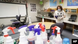 FILE - A teacher cleans a classroom in Indianapolis, June 22, 2020. Schools are making plans for students to return to classes, but with questions remaining about how instruction will happen.