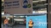 People are seen on a train platform below a sign encouraging the use of protective face masks in the city centre in Sydney