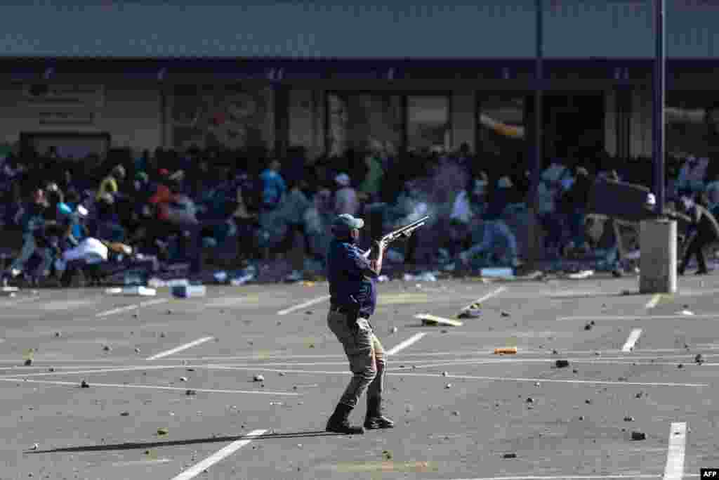 A member of the South African Police Services (SAPS) fires rubber bullets at rioters looting the Jabulani Mall in Soweto, southwest of Johannesburg.
