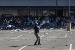 A member of the South African Police Services (SAPS) fires rubber bullets at rioters looting the Jabulani Mall in Soweto, southwest of Johannesburg, July 12, 2021.
