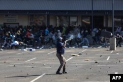 A member of the South African Police Services (SAPS) fires rubber bullets at rioters looting the Jabulani Mall in Soweto, southwest of Johannesburg, July 12, 2021.