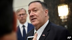 U.S. Secretary of State Mike Pompeo speaks to the media before departing from al-Bateen Air Base in Abu Dhabi, United Arab Emirates, Sept. 19, 2019, as U.S. special representative on Iran Brian Hook, left, listens. 
